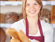 Fröhliche Bäckerin hält Baguettes in der Hand.